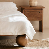 Wooden bedside table with a lamp next to a kids double bed in a bedroom setting