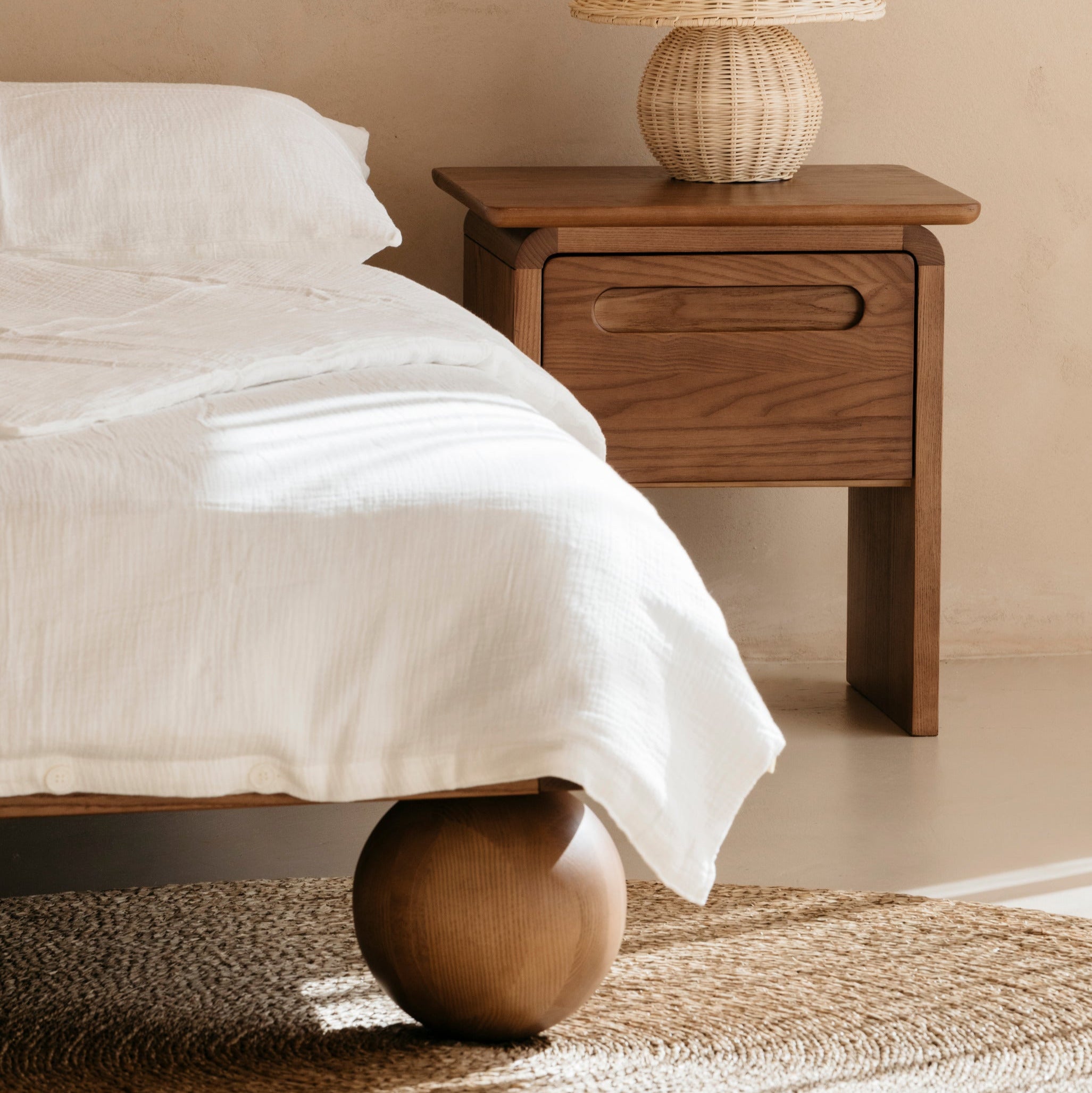 Wooden bedside table with a lamp next to a kids double bed in a bedroom setting