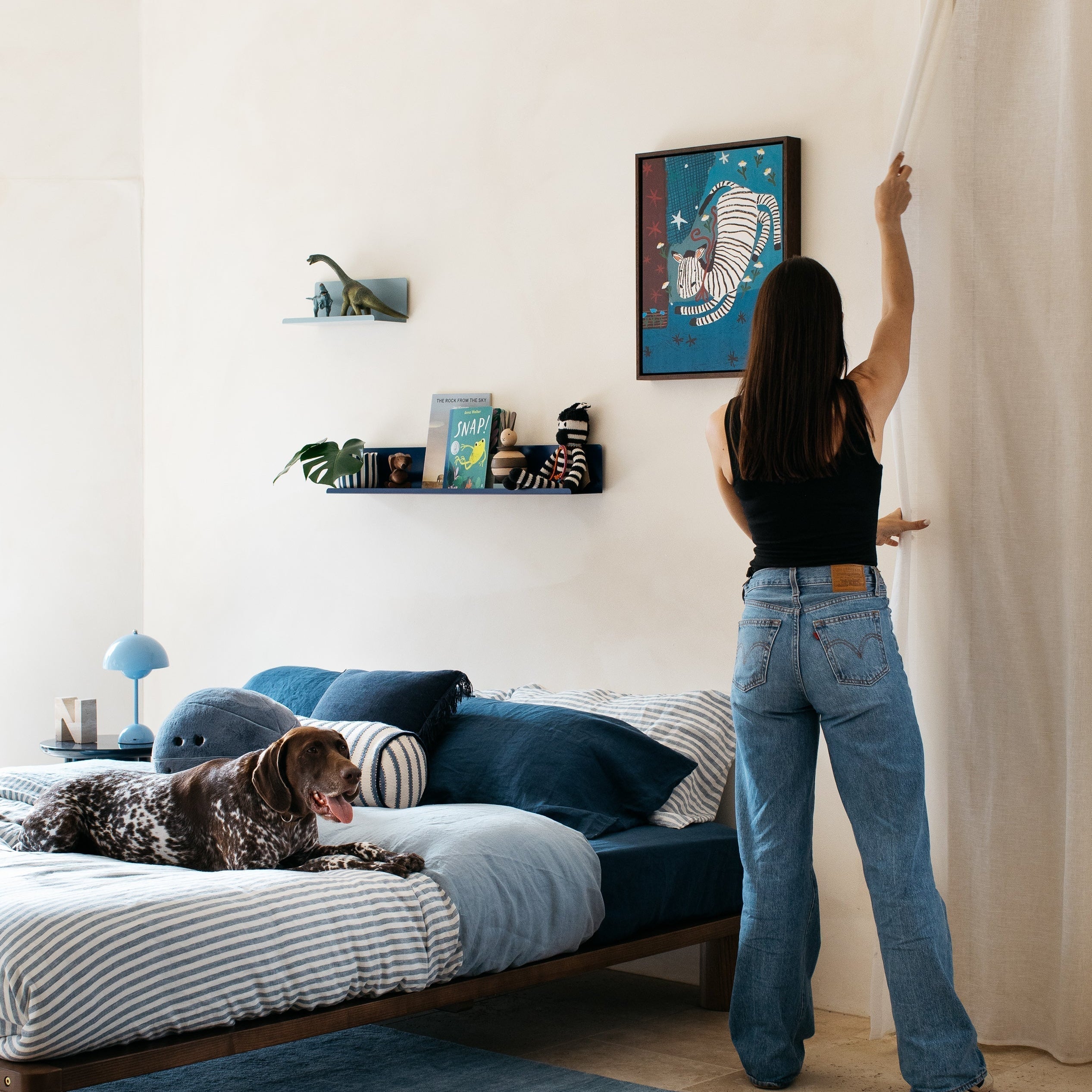 Mum adjusting blinds in styled kids room with queen bed