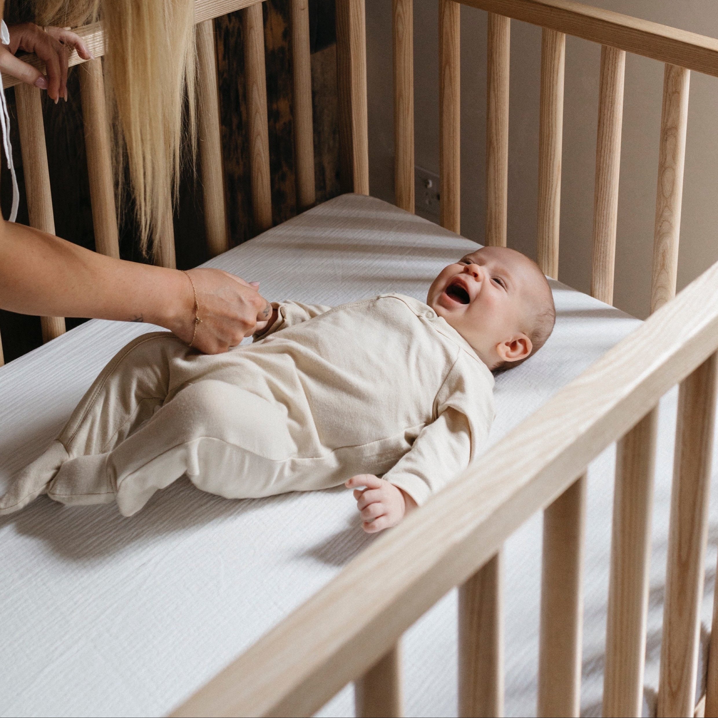 Mum and baby in cot made of solid Ashwood in nursery