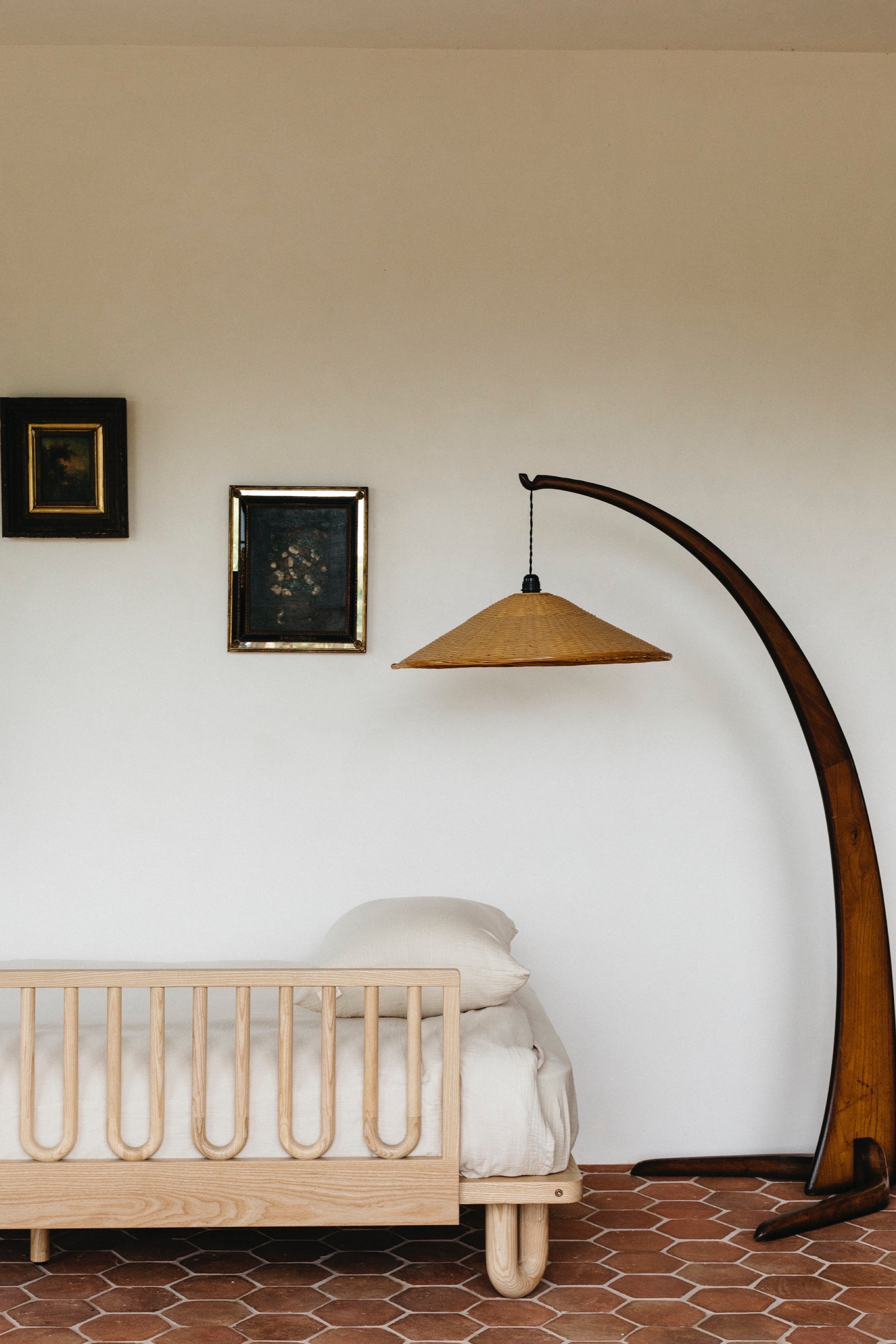 Bedroom lifestyle image showing the Arche Ashwood Toddler Bed Side Rail on a single bed with a natural wood lamp and warm toned furnishings 