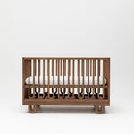 Curved design baby cot with mattress and adjustible base showing mattress at highest height