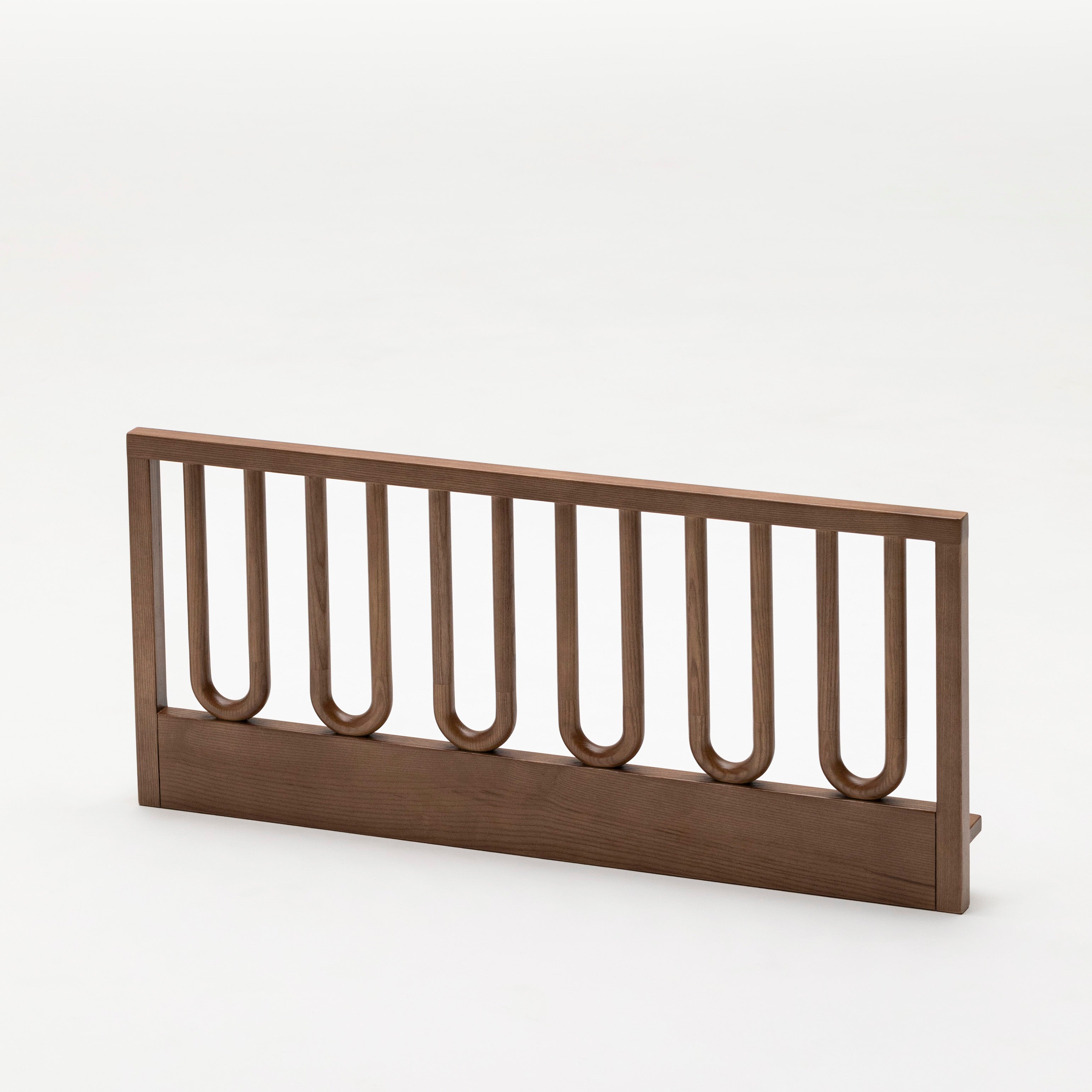 The Arche Walnut Toddler Bed Side Rail isolated on a white background to show natural wood grain and arched frame