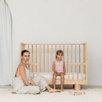 Solid wood cot showing Mum and toddler with lowered conversion rail