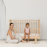 Solid wood cot showing Mum and toddler with lowered conversion rail