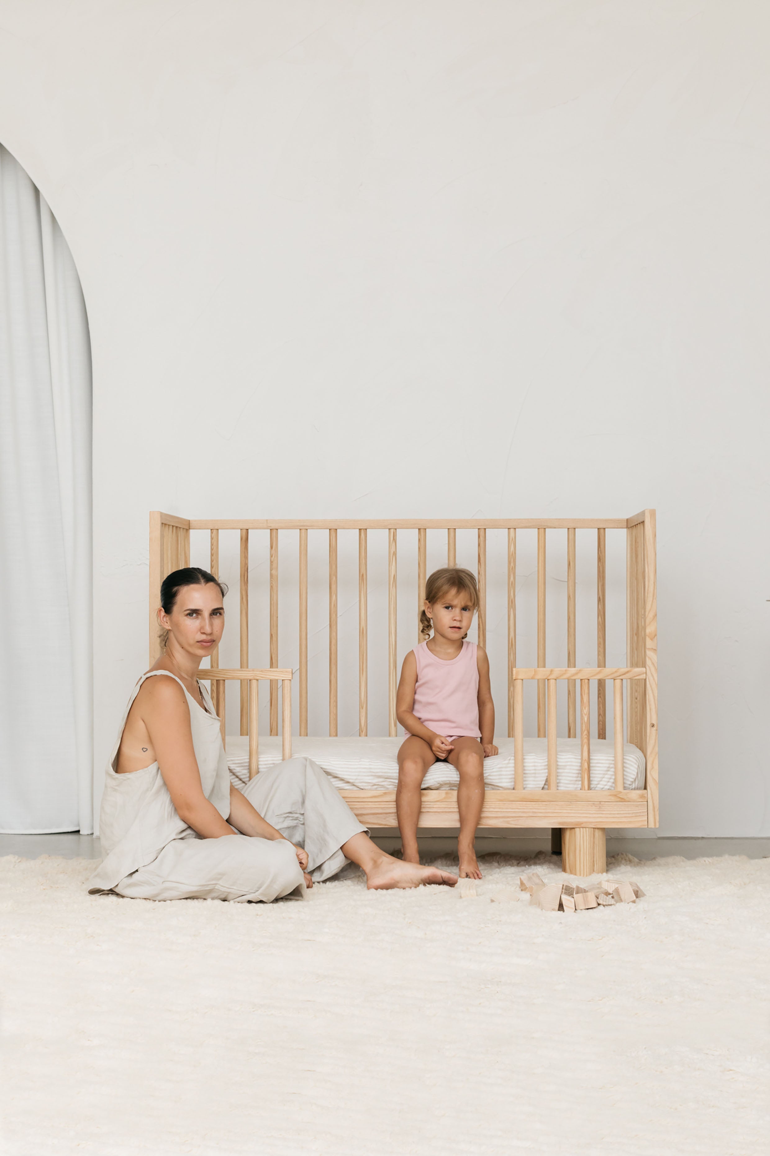 Solid wood cot showing Mum and toddler with lowered conversion rail
