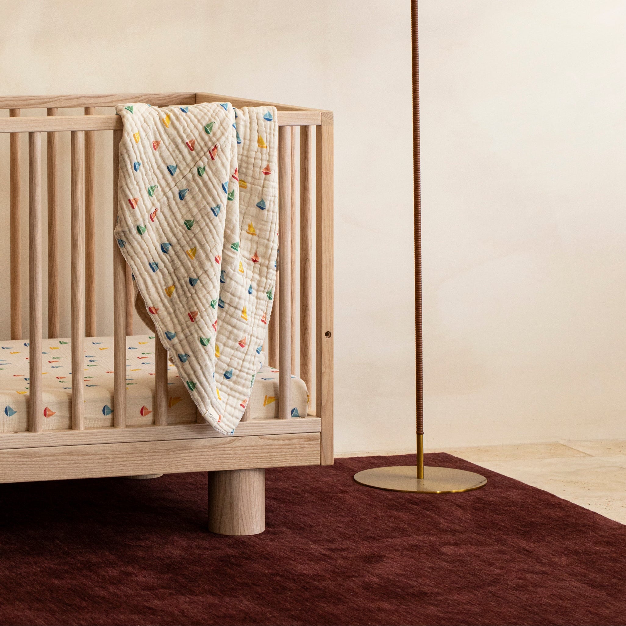 Styled Sacred Bundle Ashwood Hendrix Cot with Cotton Baby Blanket draped over the cot rail 