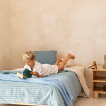 Child in bedroom reading on the Hendrix King Single Bed Ashwood with blue duvet and Hendrix Bed Side Table 