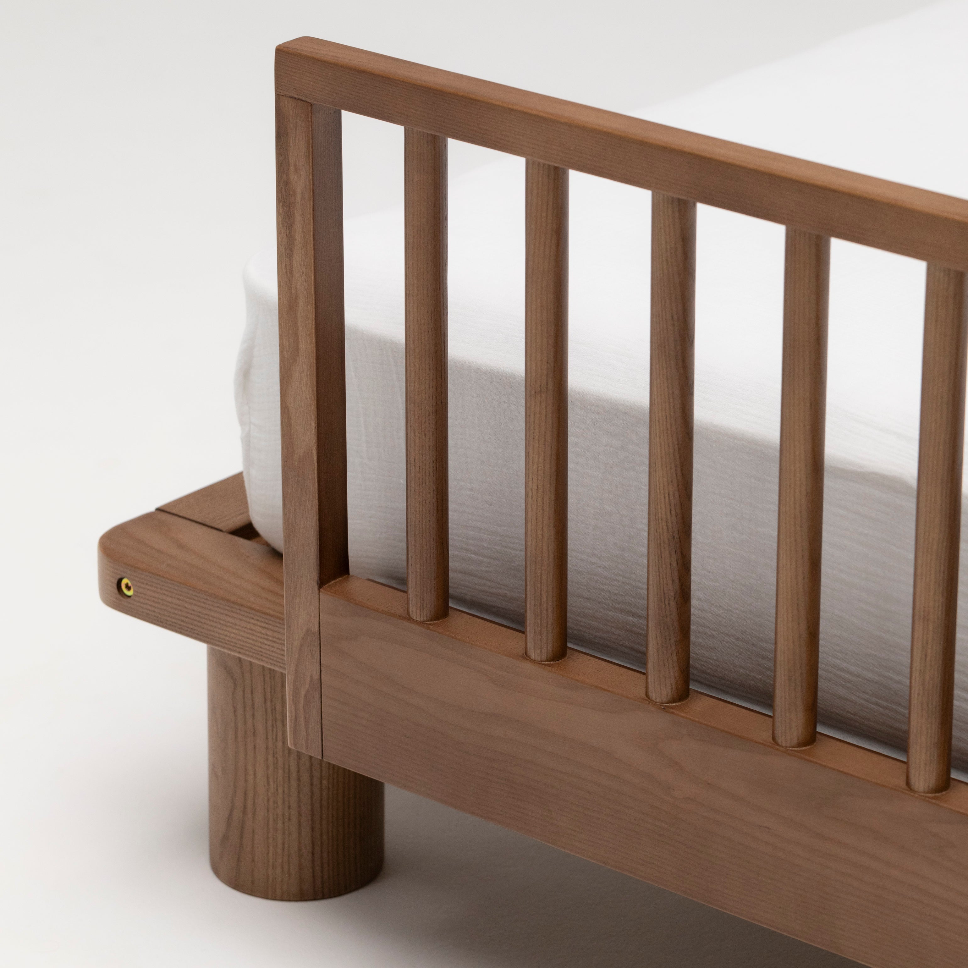 Closeup of the Hendrix Walnut Toddler Bed Side Rail on a children's king-single bed