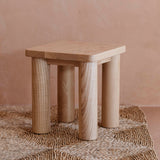 Side profile of the Hennie Kids Stool Ashwood on a natural rug in a warm playroom