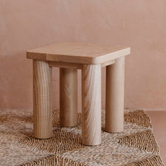 Side profile of the Hennie Kids Stool Ashwood on a natural rug in a warm playroom