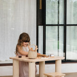 Little girl playing with toys outside sitting at a Hennie table on a Hennie Kids Stool, both in Ashwood