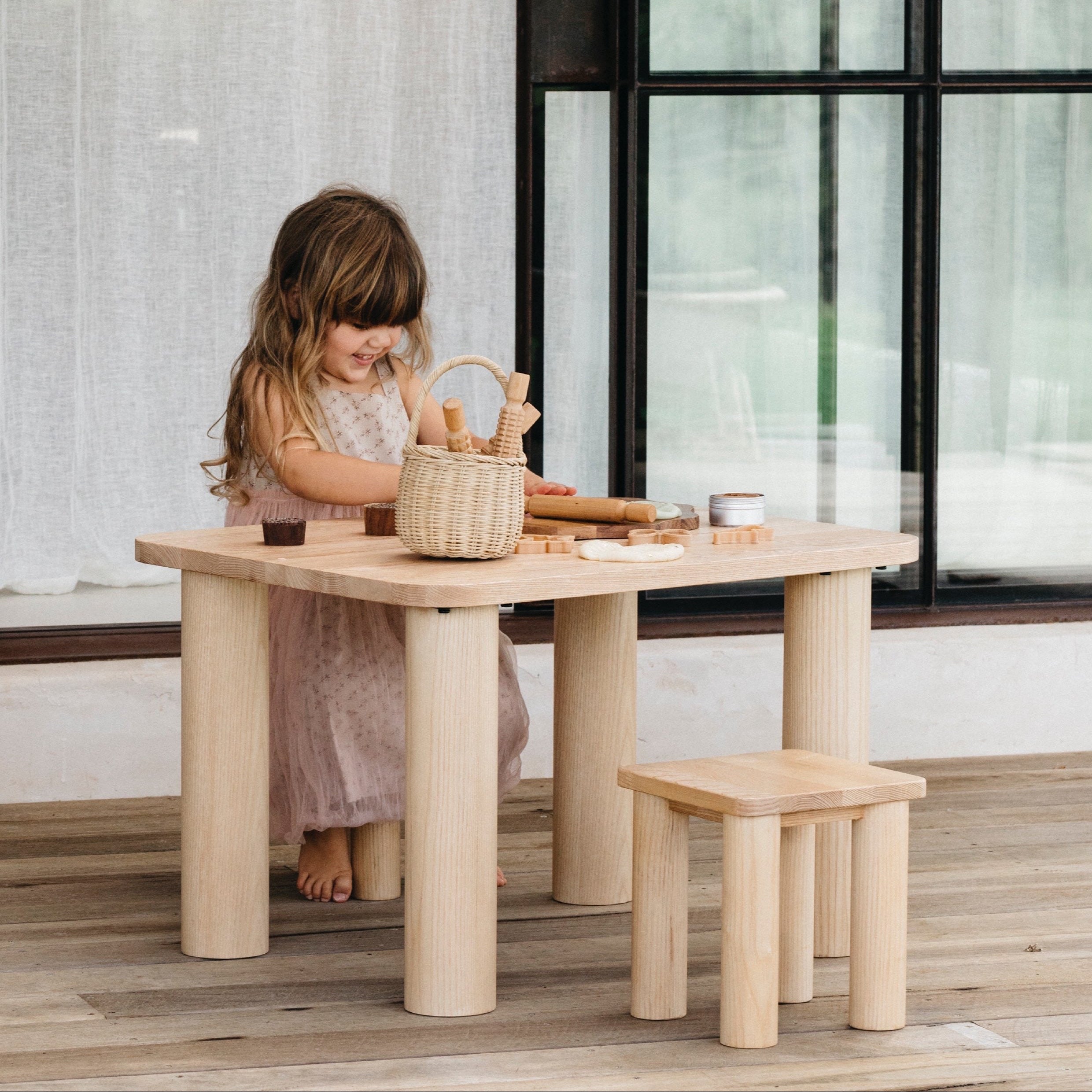 Little girl playing with toys outside sitting at a Hennie table on a Hennie Kids Stool, both in Ashwood