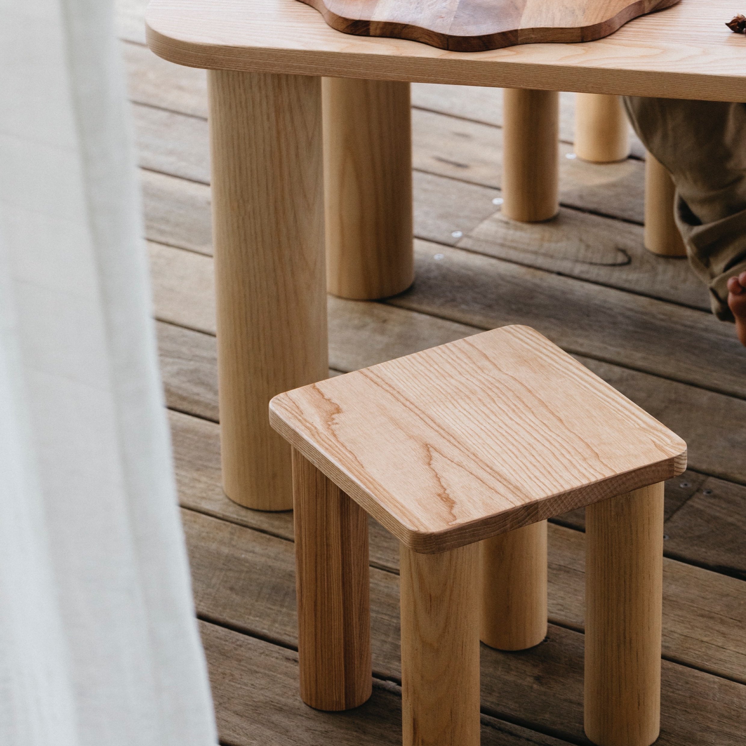 The Hennie Kids Stool Ashwood with the matching table outdoors on a balcony showing kids baking playtime toys