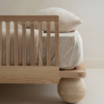 Closeup of the Zali Ashwood Toddler Bed Side Rail on a single bed with textured white duvet