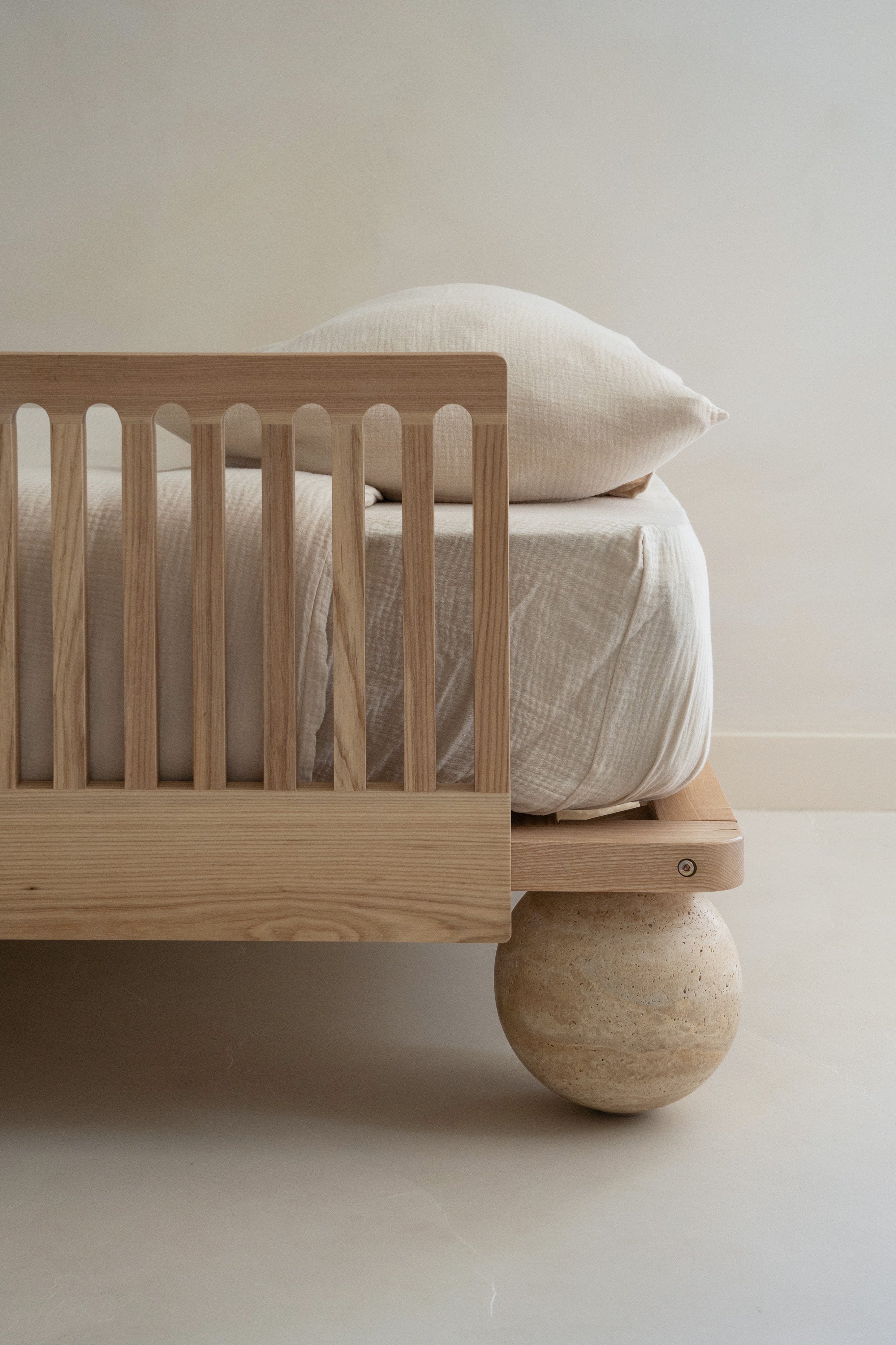 Closeup of the Zali Ashwood Toddler Bed Side Rail on a single bed with textured white duvet