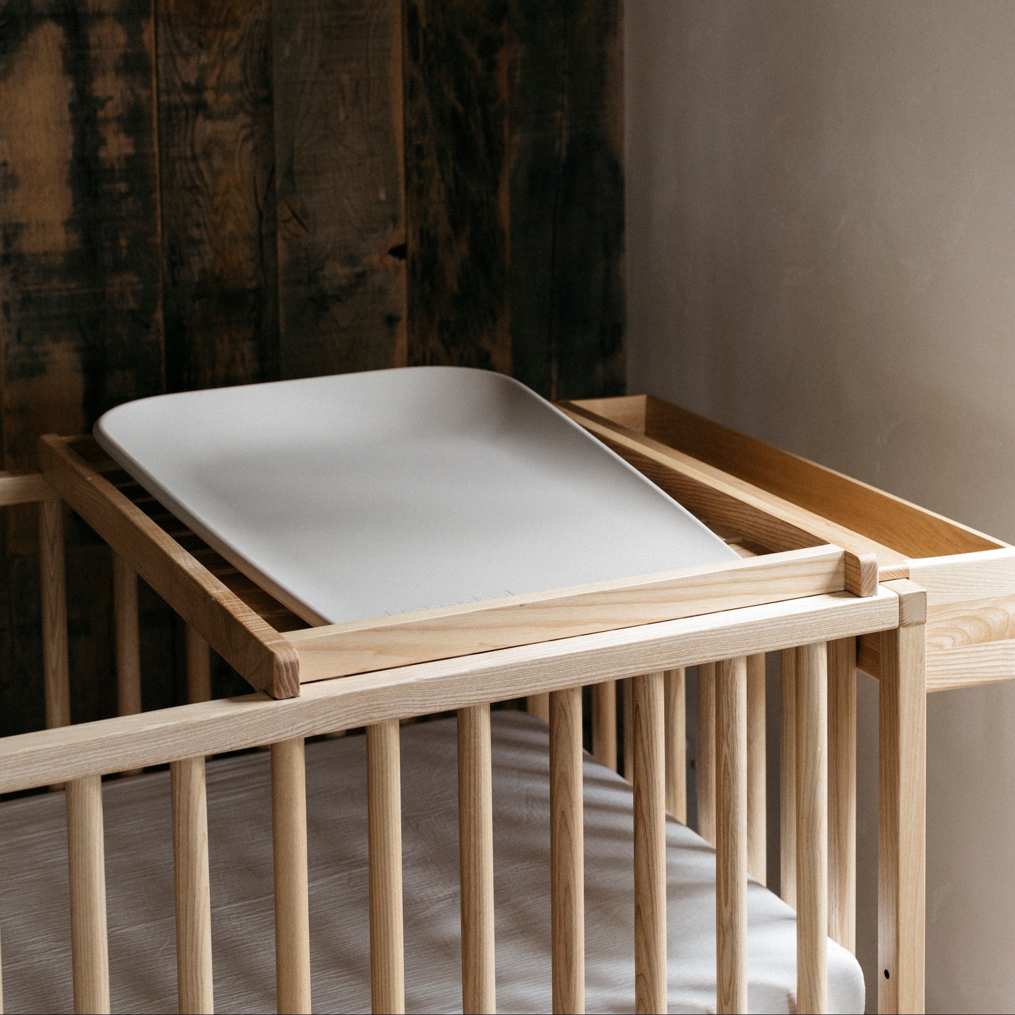 Leander Matty Mini Change Mat - Cappuccino siting on top of he Ashwood Space Saver on a Sacred Bundle Baby Cot