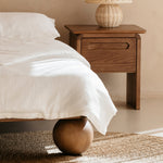 Wooden bedside table with a lamp next to a kids double bed in a bedroom setting