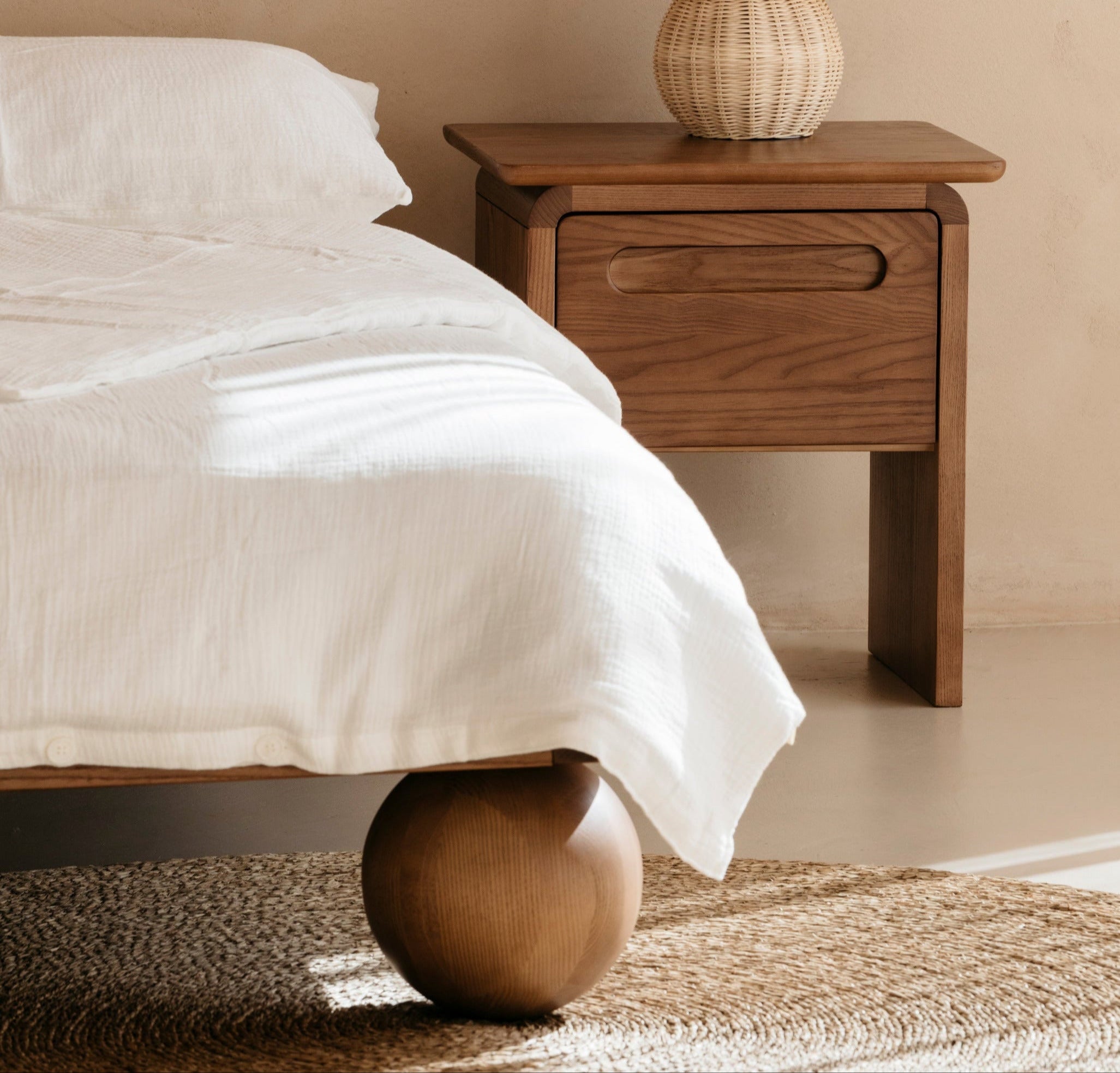 Wooden bedside table with a lamp next to a kids double bed in a bedroom setting