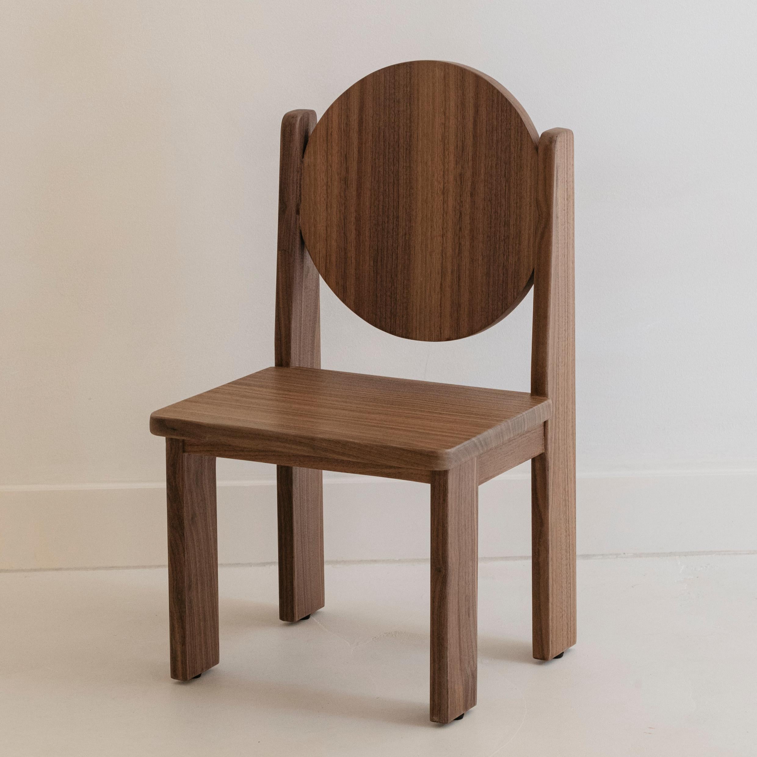 A brown solid walnut wood children's chair with a rounded backrest and seat, displayed against a white background.
