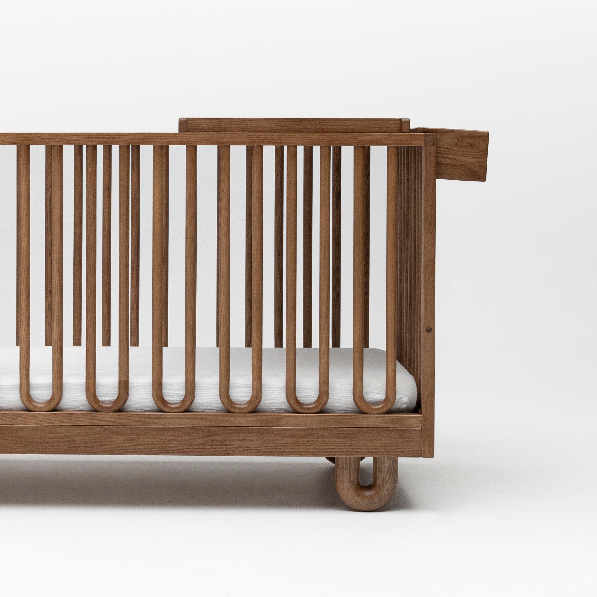 The Walnut Space Saver and Caddy attached to the Sacred Bundle Arche Cot to show how the change table is used.
