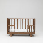 Solid timber baby cot in walnut showing toddler conversion side lowered