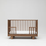 Solid timber baby cot in walnut showing toddler conversion side lowered