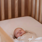 Baby sleeping on mattress in solid wood Zali cot