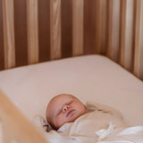 Baby sleeping on mattress in solid wood Zali cot