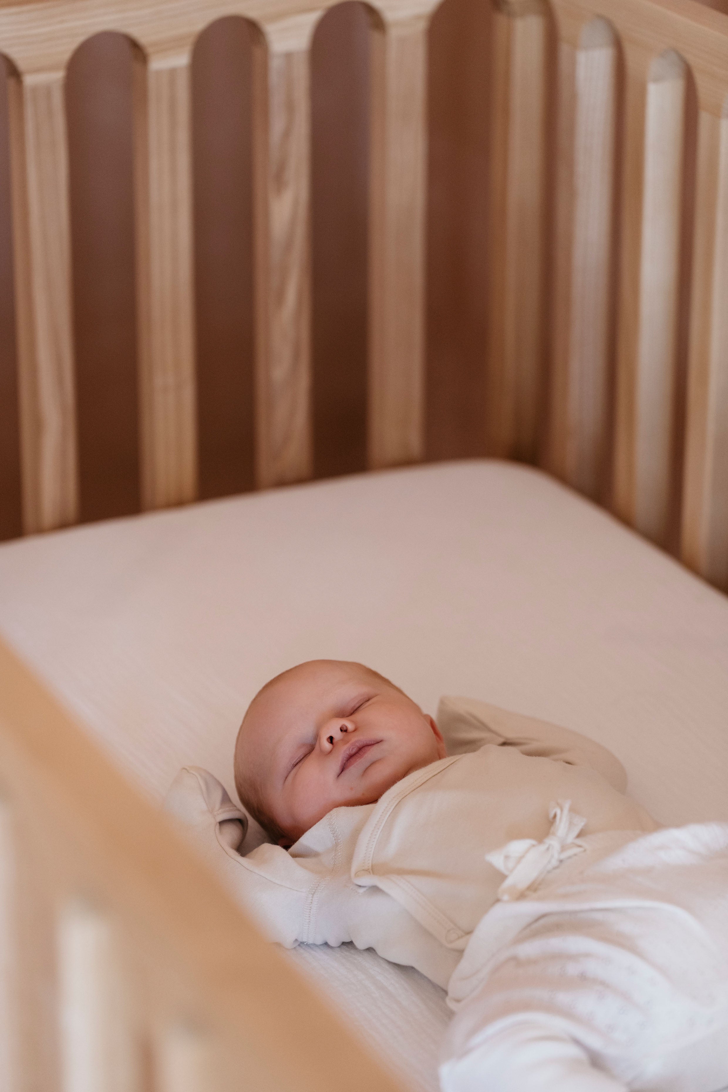 Baby sleeping on mattress in solid wood Zali cot