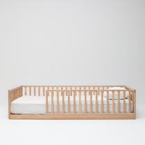 Front view of the Zali Ashwood Floor Bed made up with white single mattress, sheets and pillow