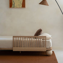 Studio image showing the Zali Ashwood Toddler Bed Side Rail on an Ashwood King Single Bed with Travertine legs and warm brown furnishings