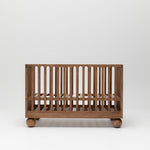 Zali Walnut Baby Cot featuring ball legs and adjustable base.