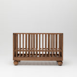 Zali Walnut Baby Cot featuring ball legs and adjustable base.