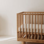 Side view of Ashwood cot showing Hendrix design featuring cylinder legs and solid wood frame with adjustable base